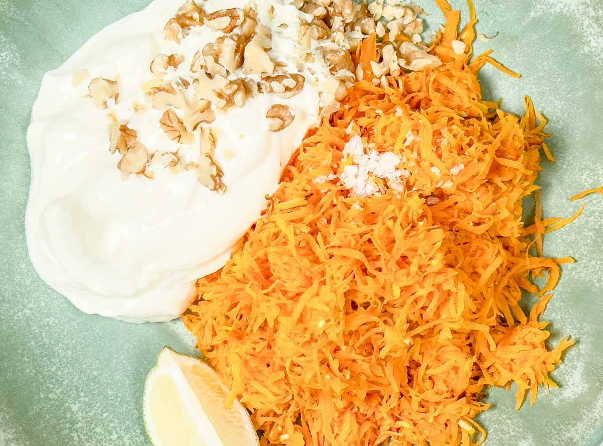 grated carrots, cream, walnut in a green bowl