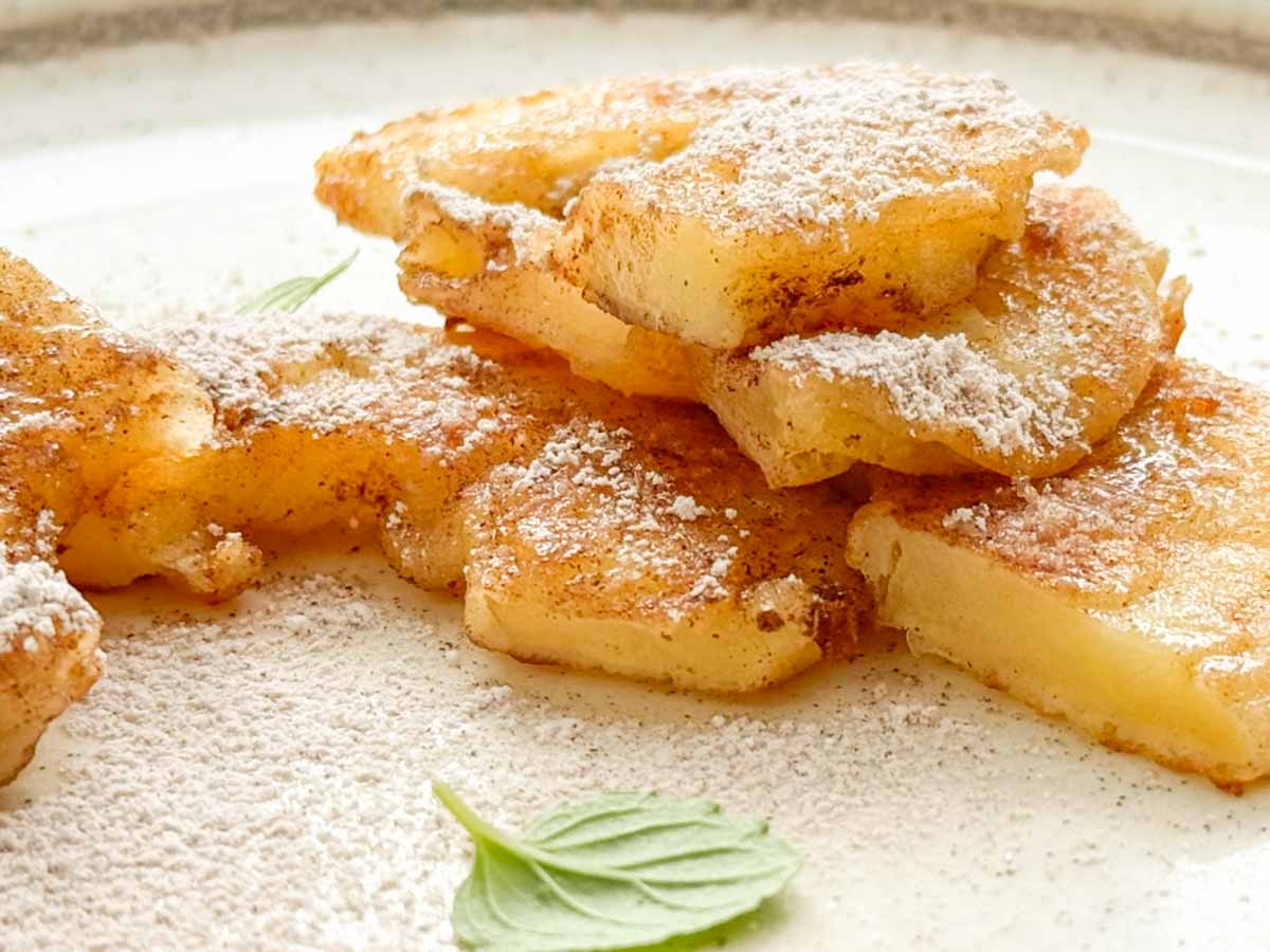 cut apple fritters Apfelküchlein with sugar on plate